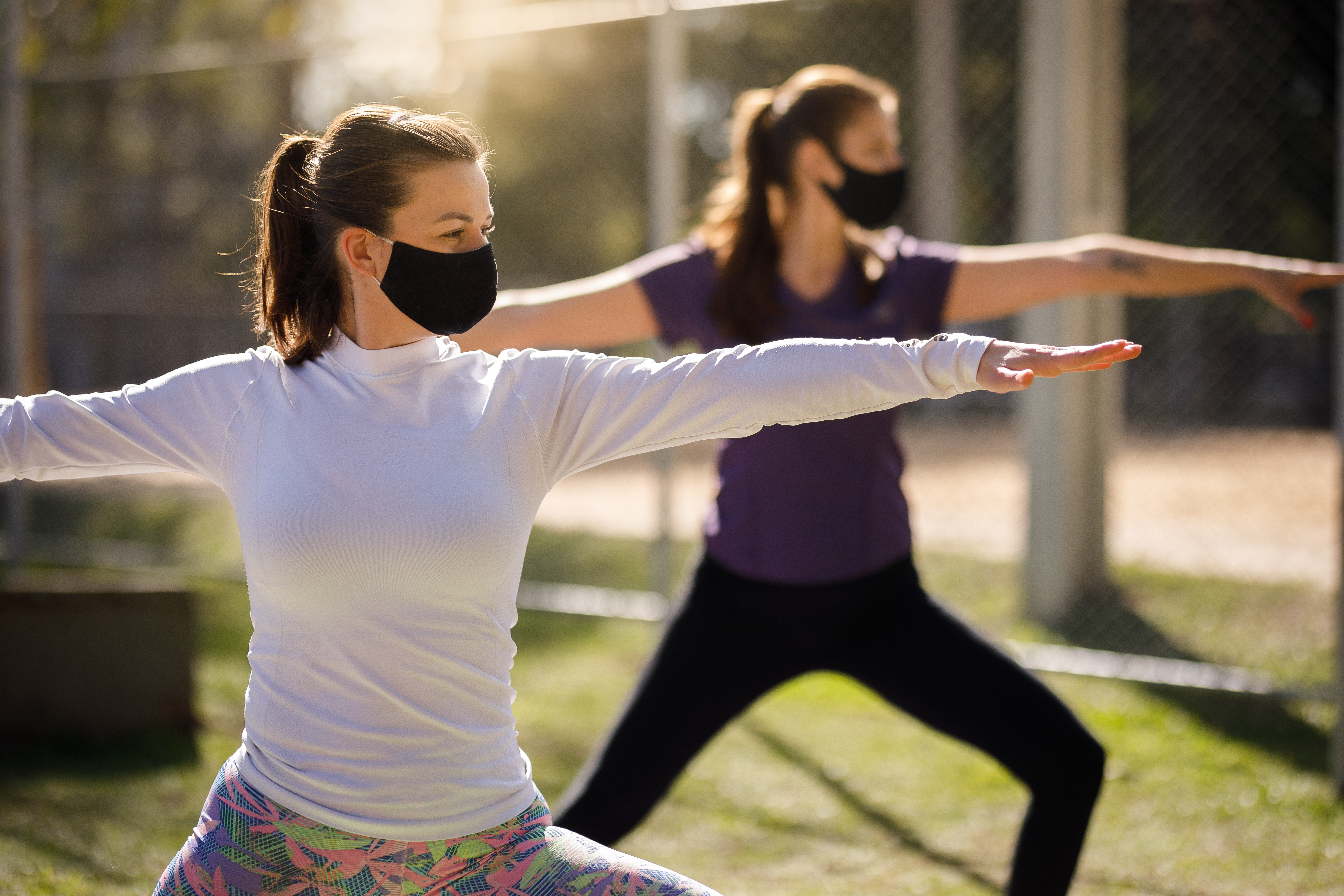 women doing yoga with masks on in a park