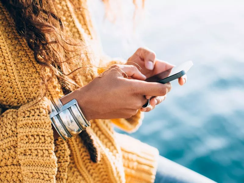 woman holding phone wearing yellow sweater