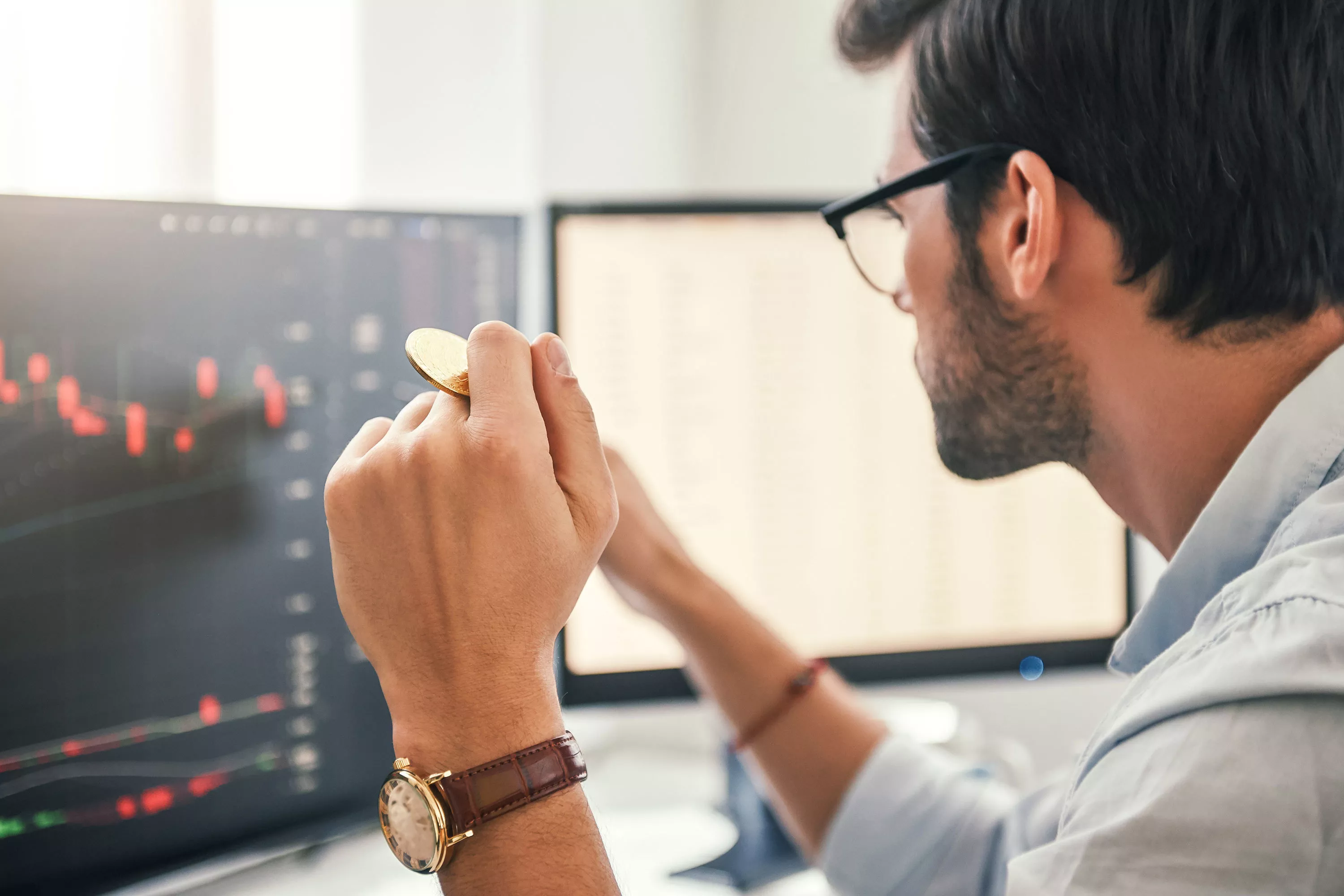 man looking at computer holding a coin