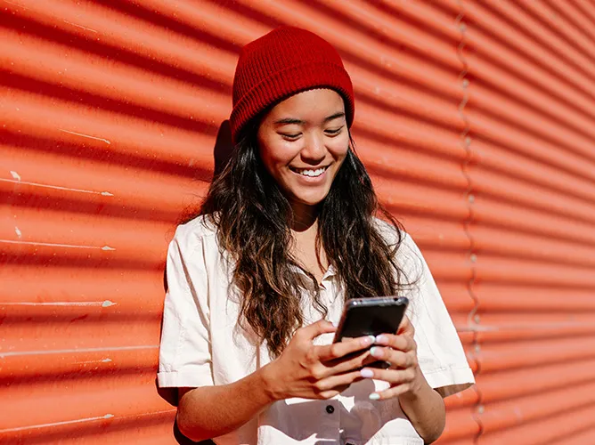 Woman on her phone outside with a hat on