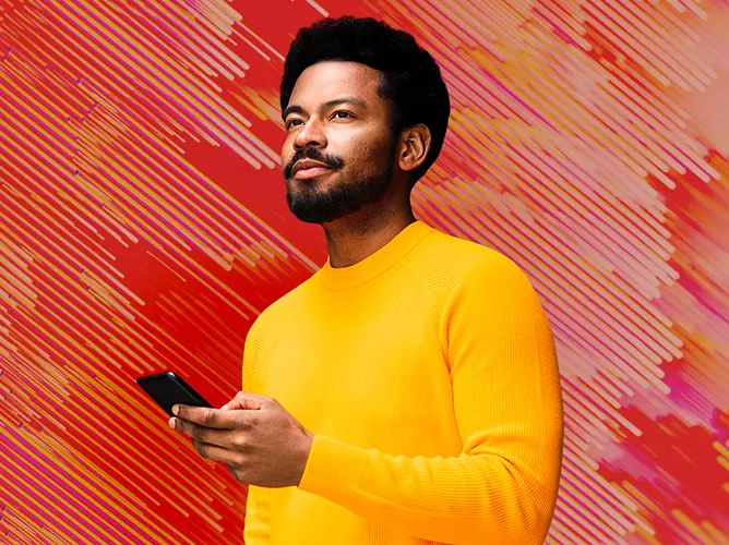 Man in front of orange backdrop smiling teaser